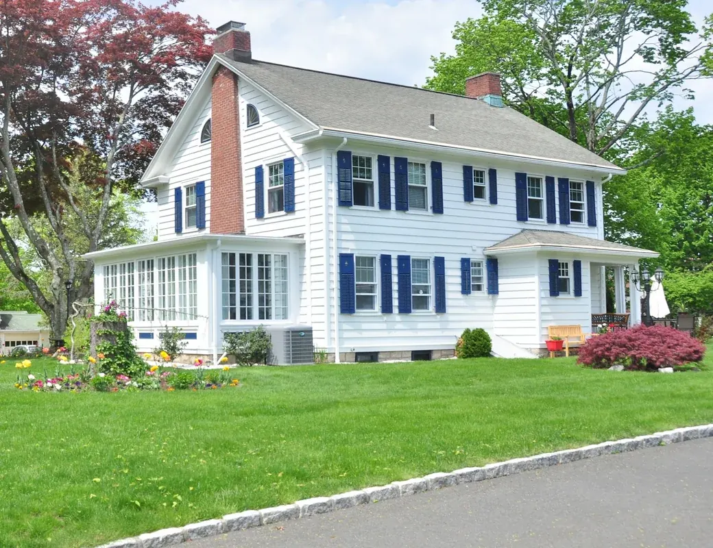 A two-storey American family home with blue shutters and a front lawn, the kind of property a Home Insecto inspection covers